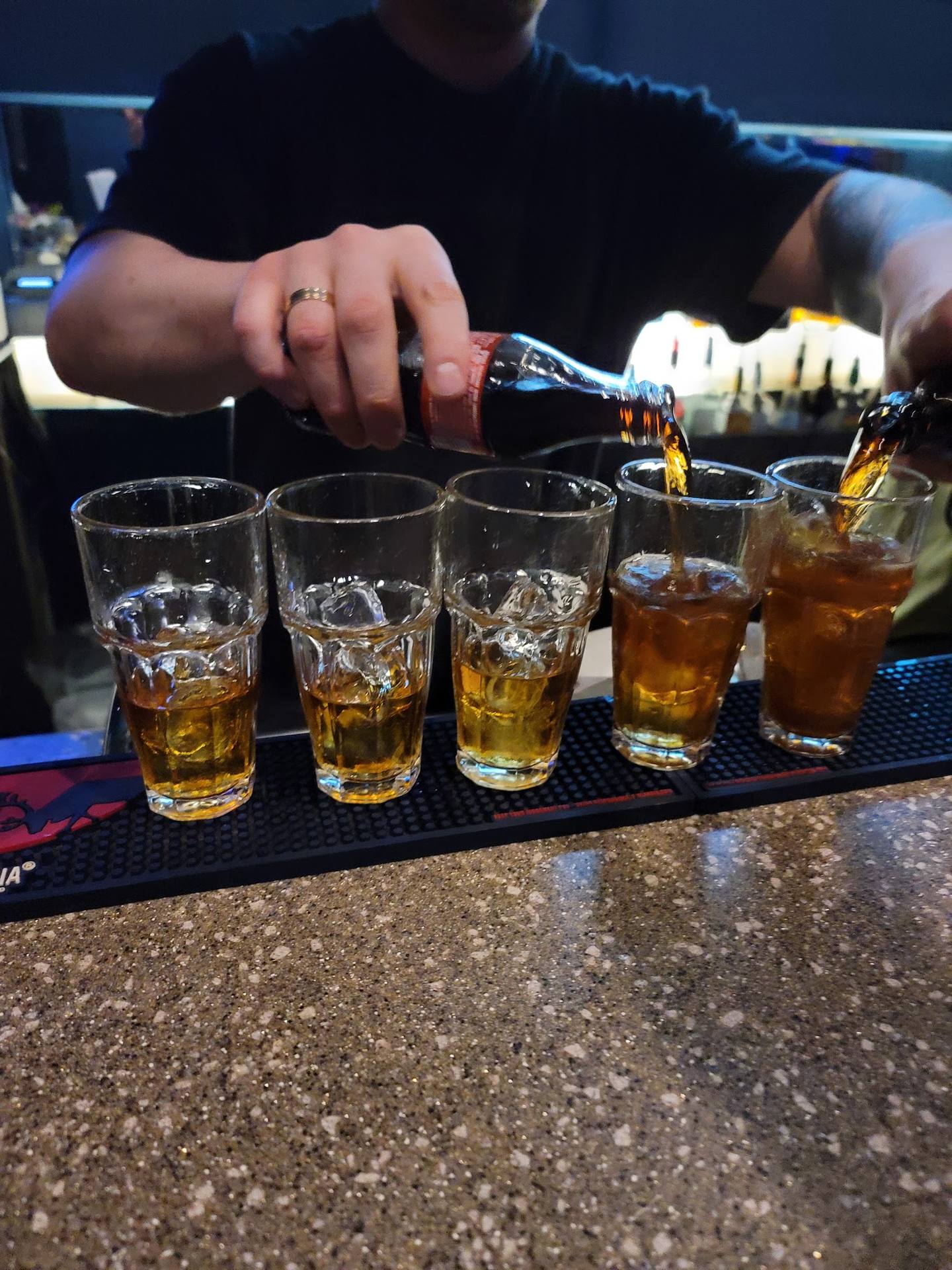Bartender pouring whiskey into a tasting flight of glasses