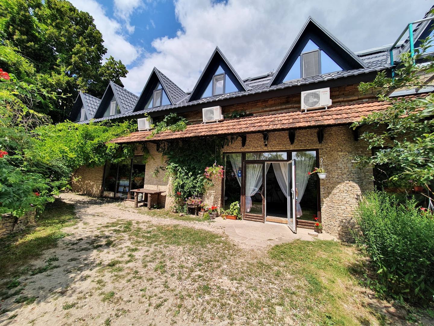 Charming stone cottage with distinctive pitched roof gables and ivy-covered walls, featuring direct courtyard access