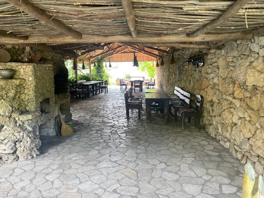 Stone terrace with rustic wooden roof and seating area