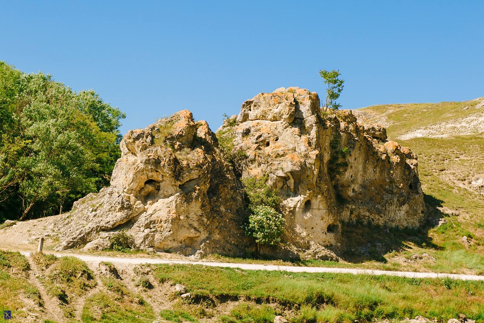 Historic fortress ruins with distinctive rocky outcrops overlooking green valley landscape