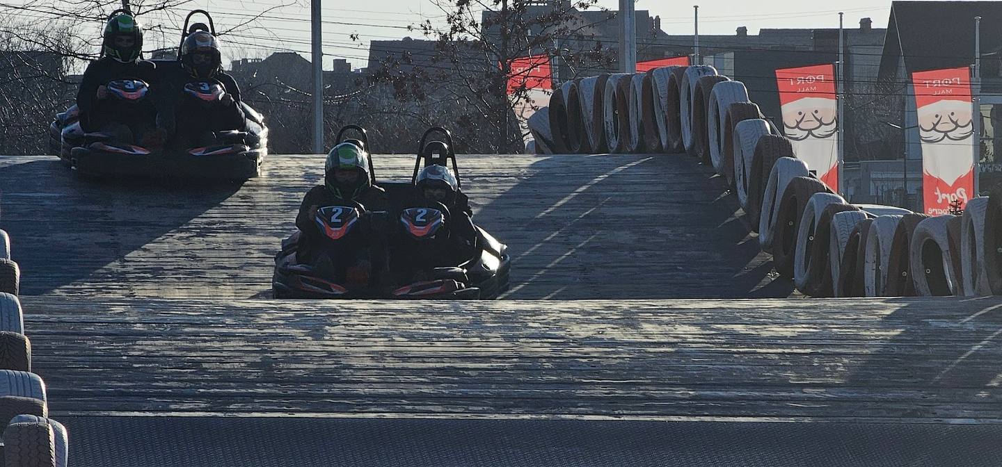 Go-kart racing on outdoor track with tire barriers and safety markers visible