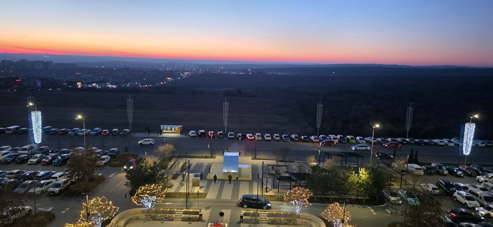 Aerial view of illuminated venue at dusk with surrounding landscape and parking areas