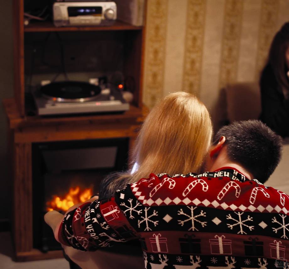 Couple relaxing by fireplace and entertainment system in warm interior