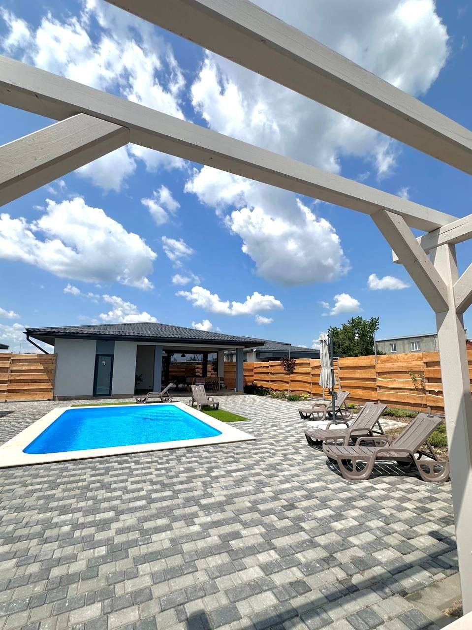 Modern resort terrace with pergola, swimming pool, and guest accommodations