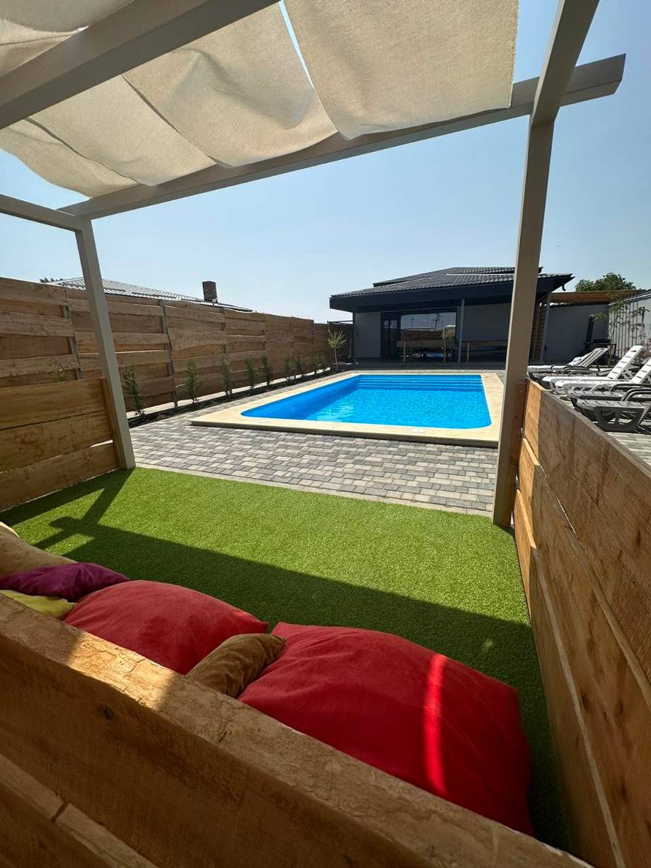 Private terrace with heated pool, pergola seating, and manicured lawn area