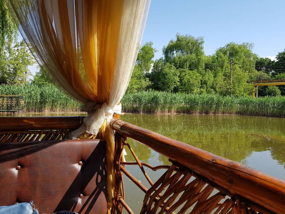 Traditional wooden boat sail on calm river with reeds and nature backdrop