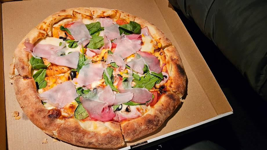 Wood-fired pizza with ham and fresh basil on parchment