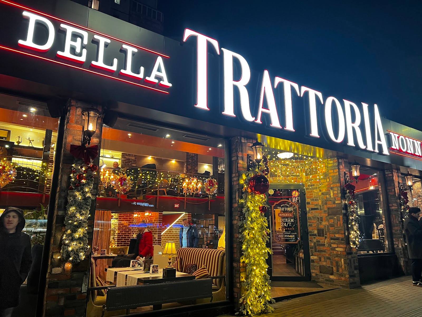 Della Trattoria storefront illuminated at night with ivy and elegant signage