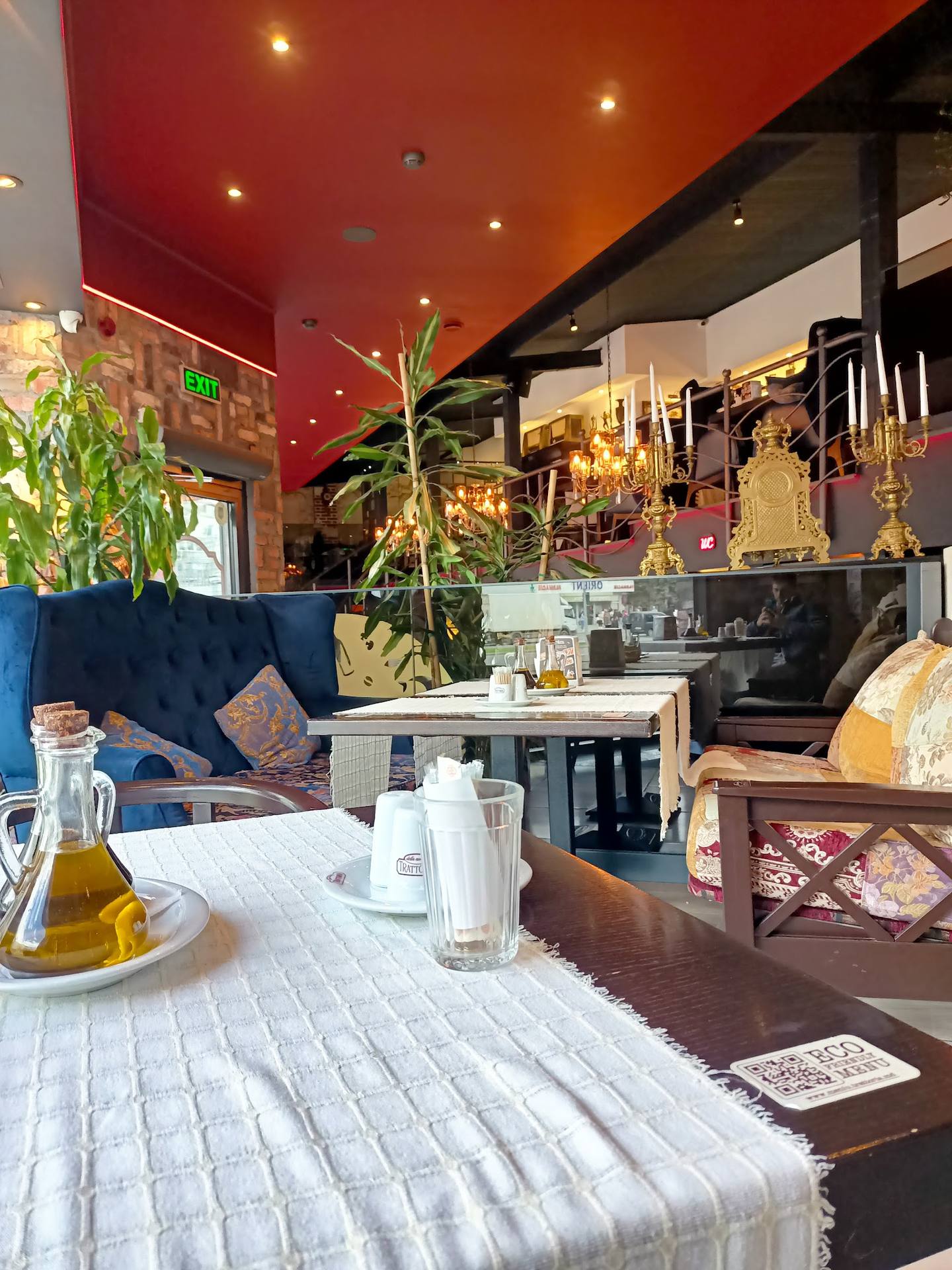 Warm modern café interior with blue velvet seating, dramatic red ceiling, and contemporary bar setup