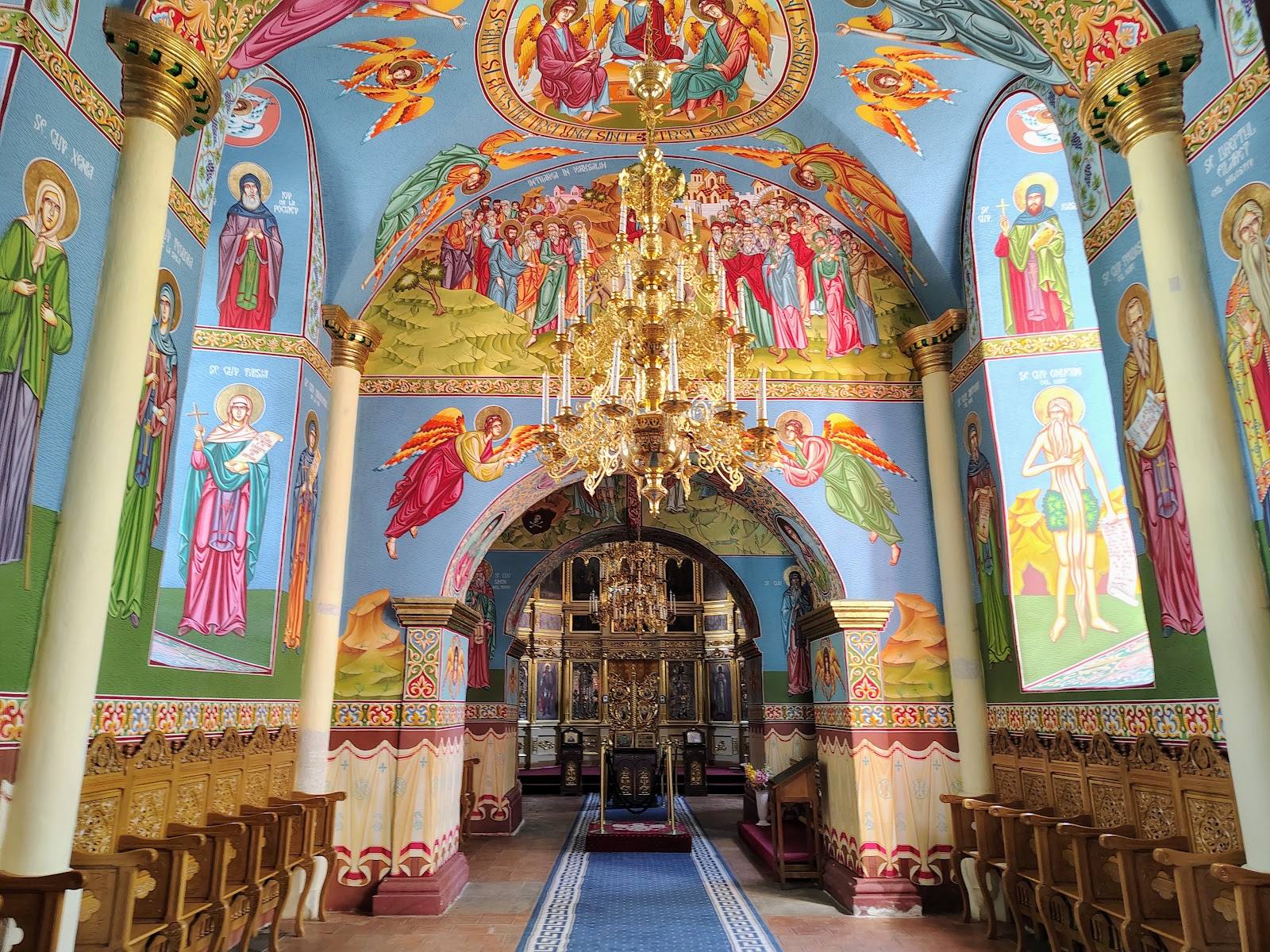 Ornate Orthodox monastery chapel with Byzantine frescoes, gilded iconostasis, and vaulted ceiling