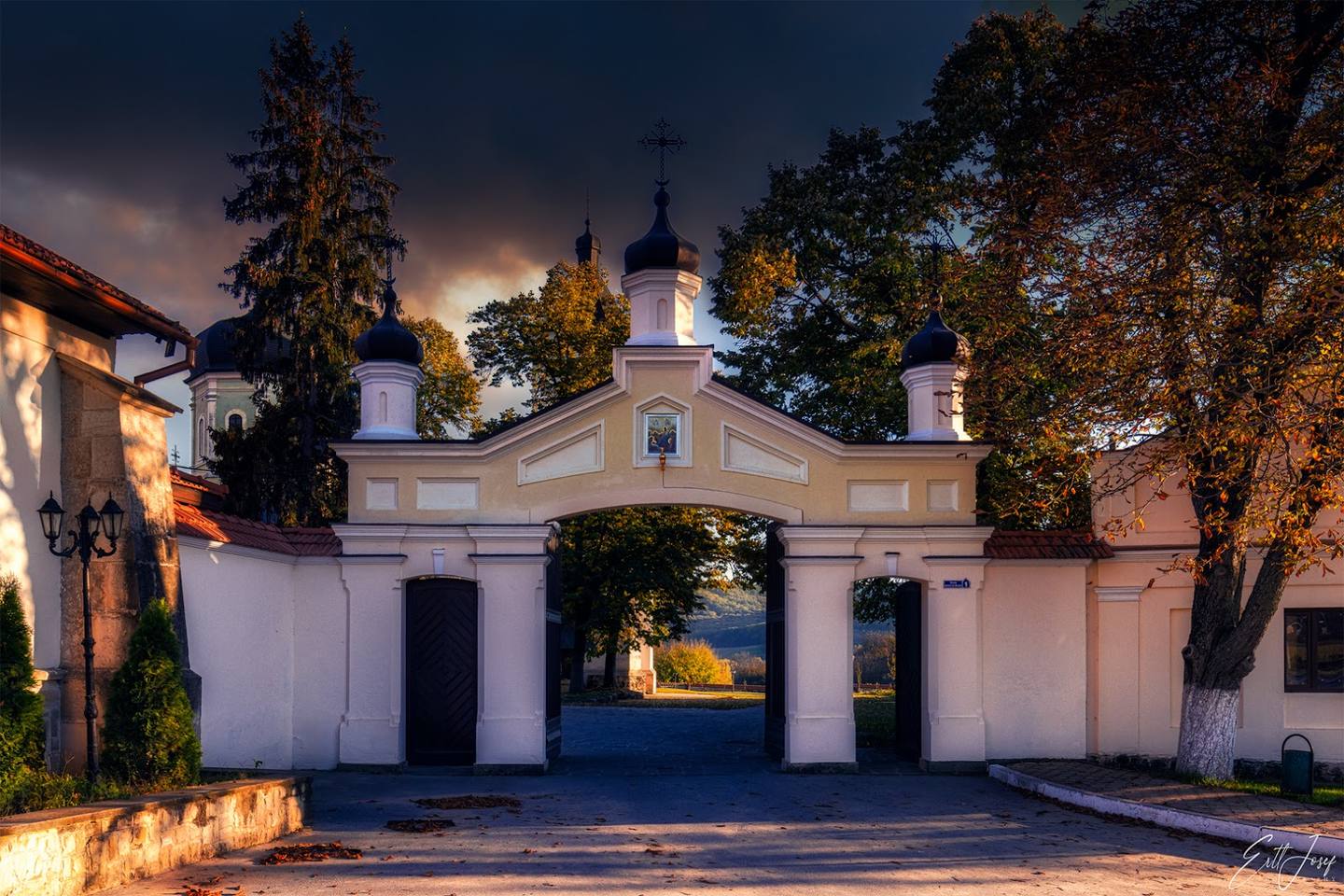 Historic monastery chapel facade illuminated at dusk with classical white architecture and dual cupolas
