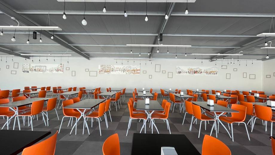 Modern event space with bright lighting, orange seating, and flexible open floor plan