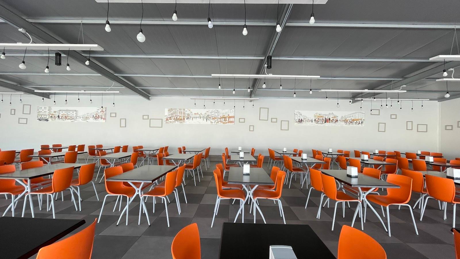 Modern event space with bright lighting, orange seating, and flexible open floor plan