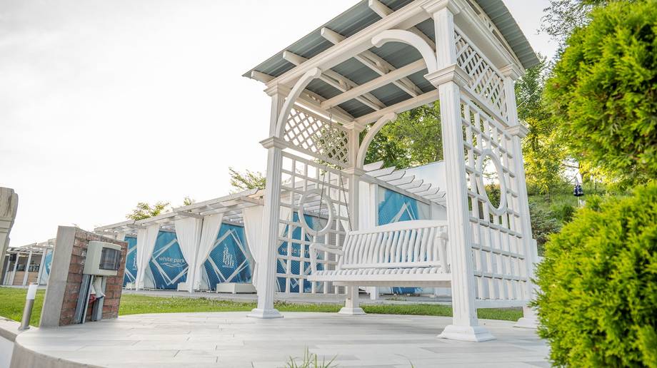 White pergola pavilion with blue geometric art installations and manicured landscaping