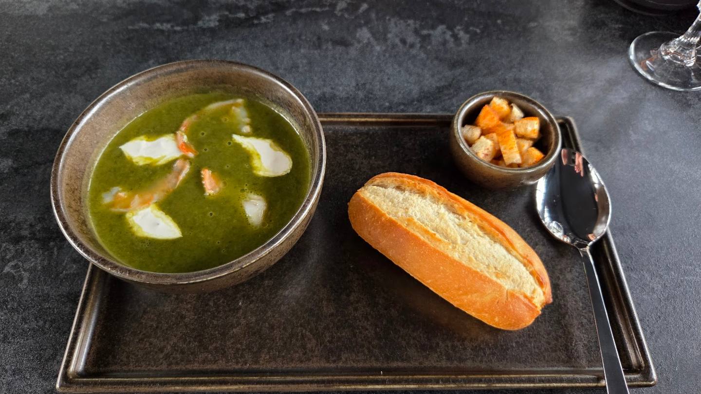Soup served with bread and croutons on dark slate placemat