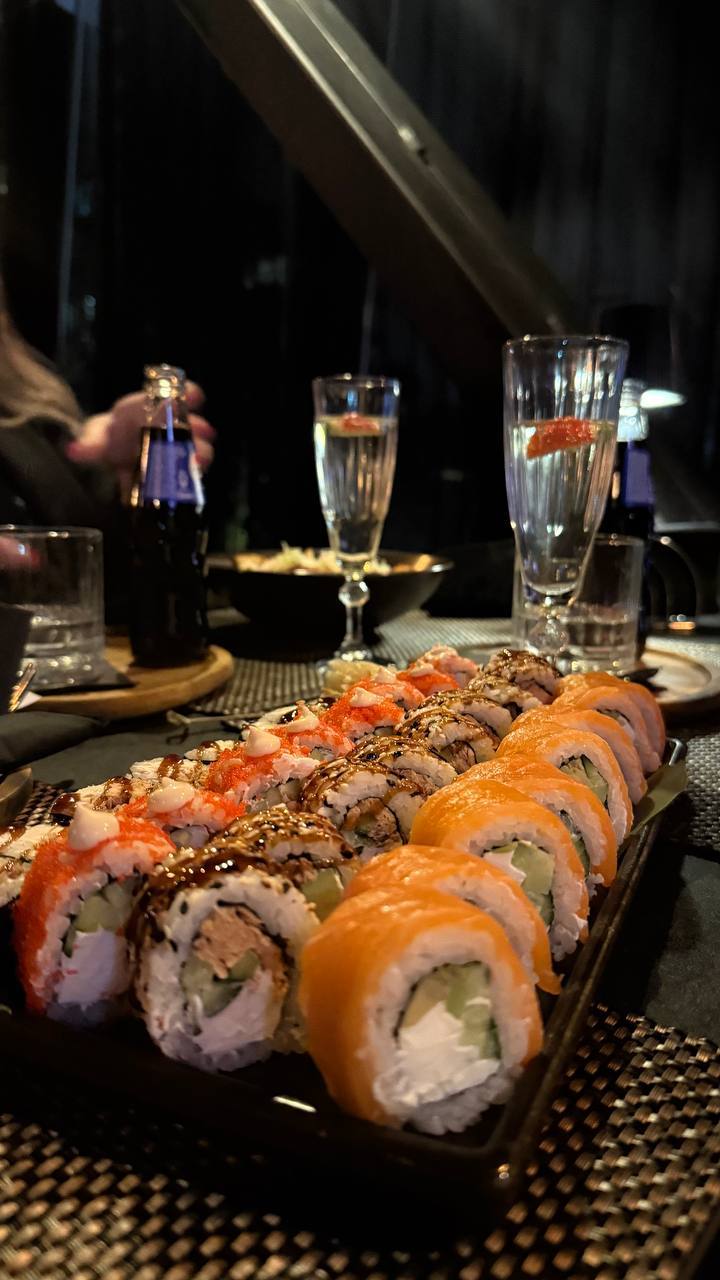 Assorted sushi rolls with salmon and garnish served with cocktails