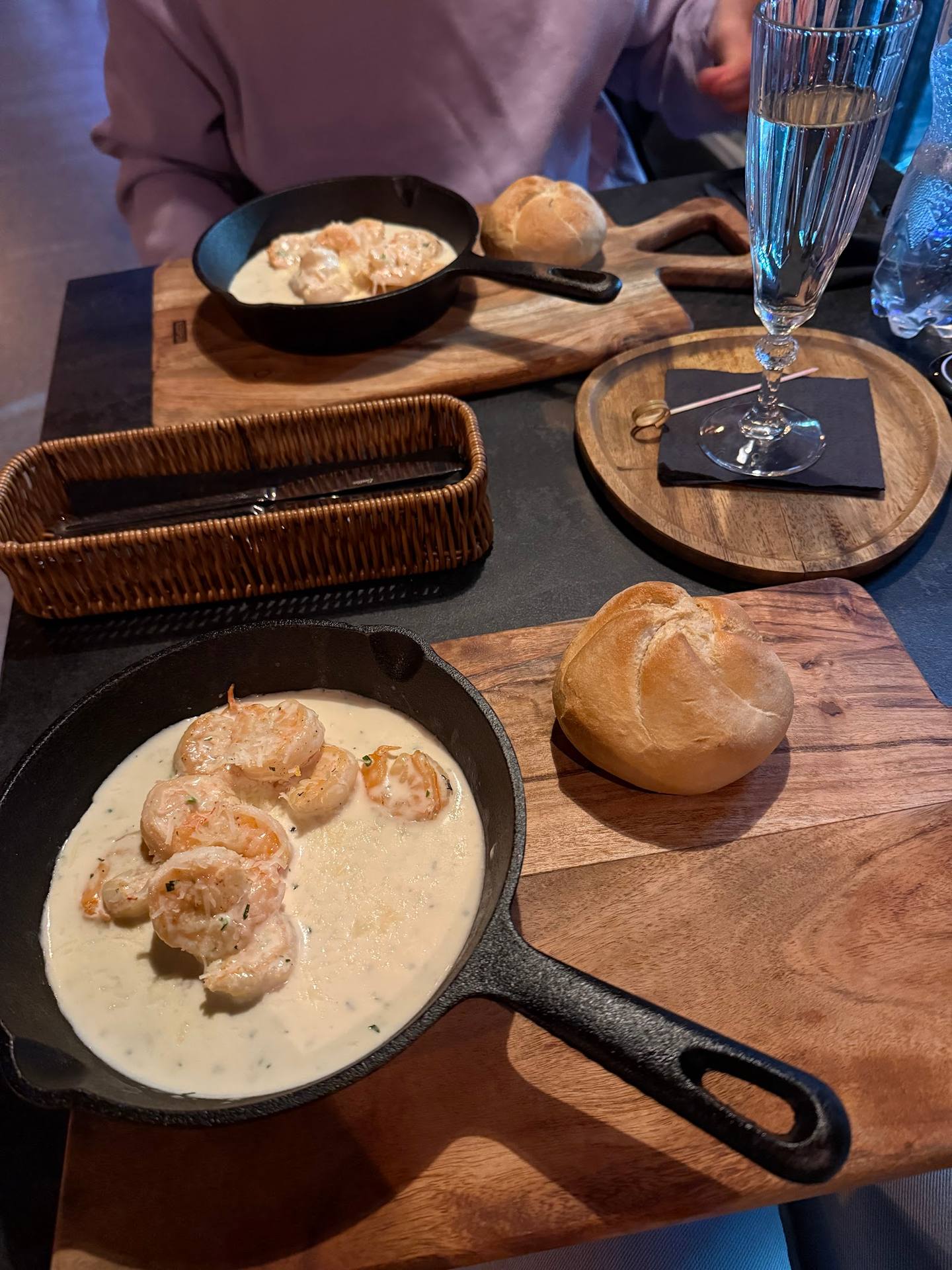 Creamy mushroom dumplings and bread rolls served in cast-iron skillet on wooden board