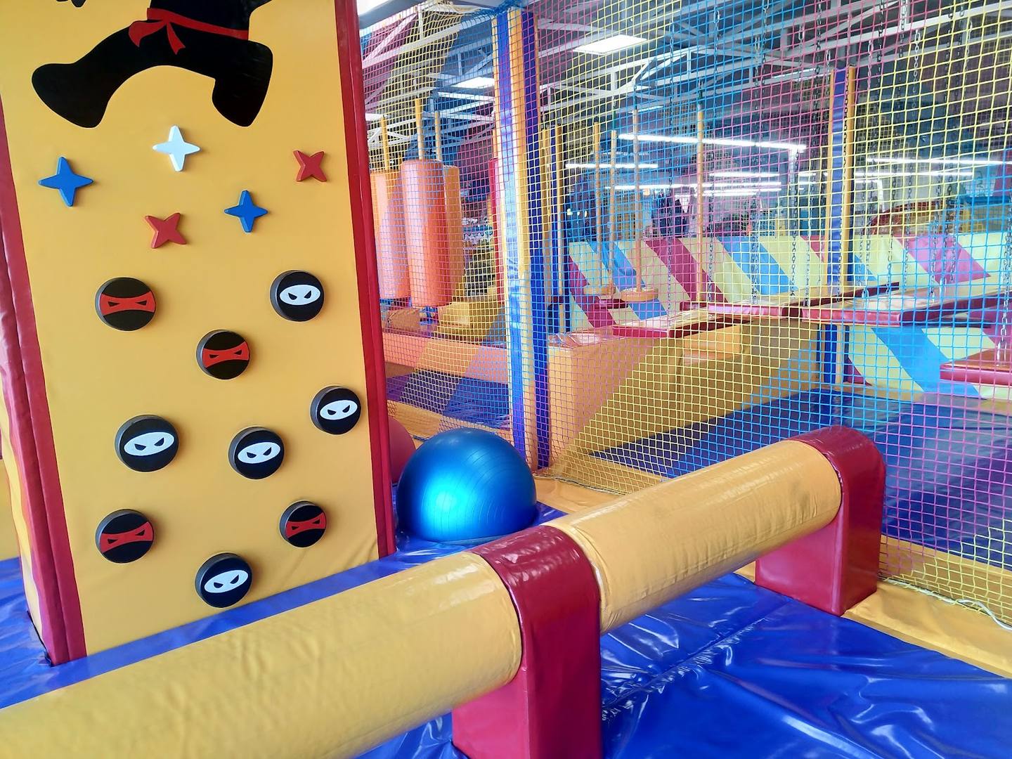 Colorful kids' play structure with climbing walls, foam logs, and netting