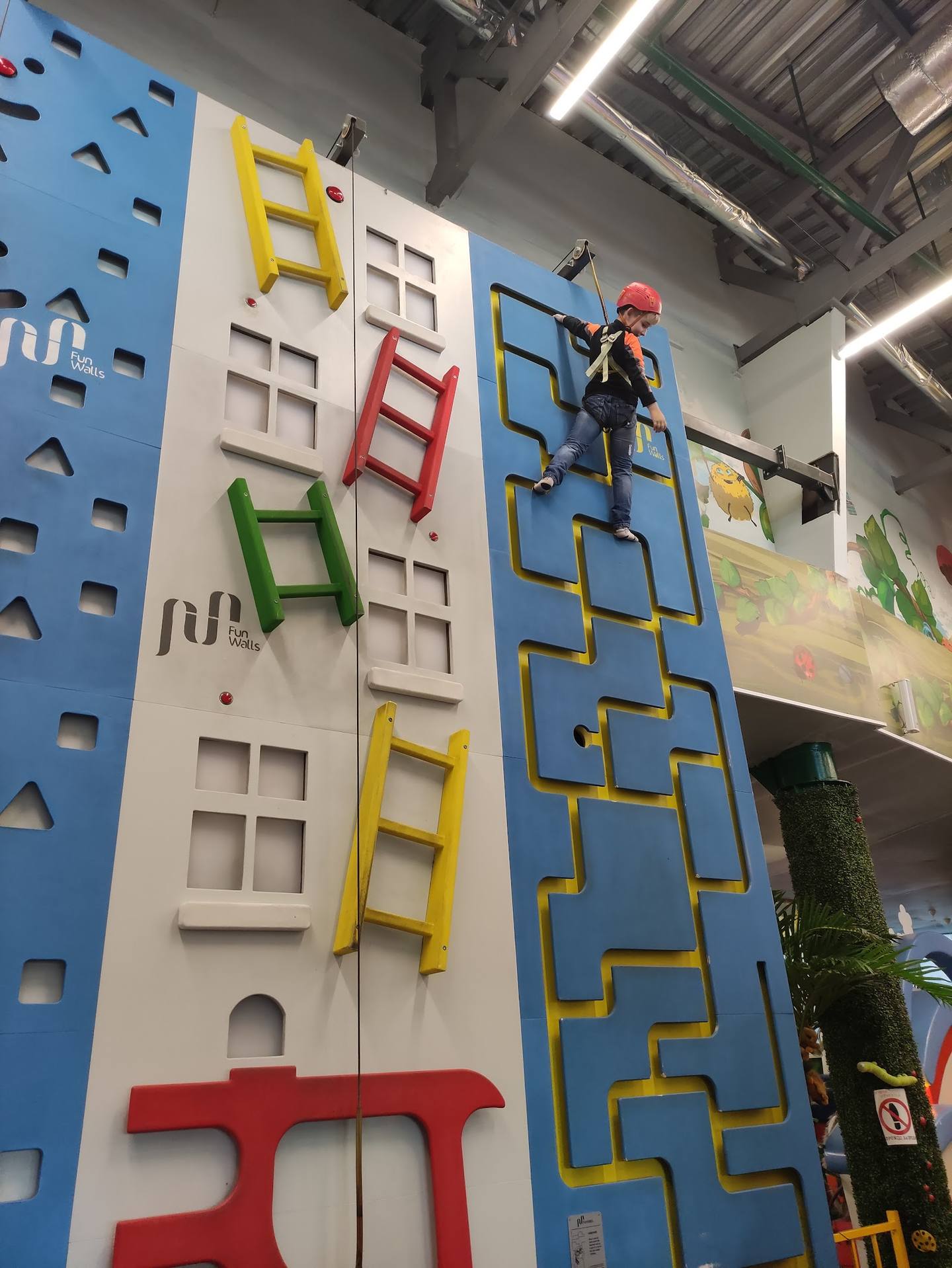 Indoor climbing wall with colorful routes and climber ascending challenge course