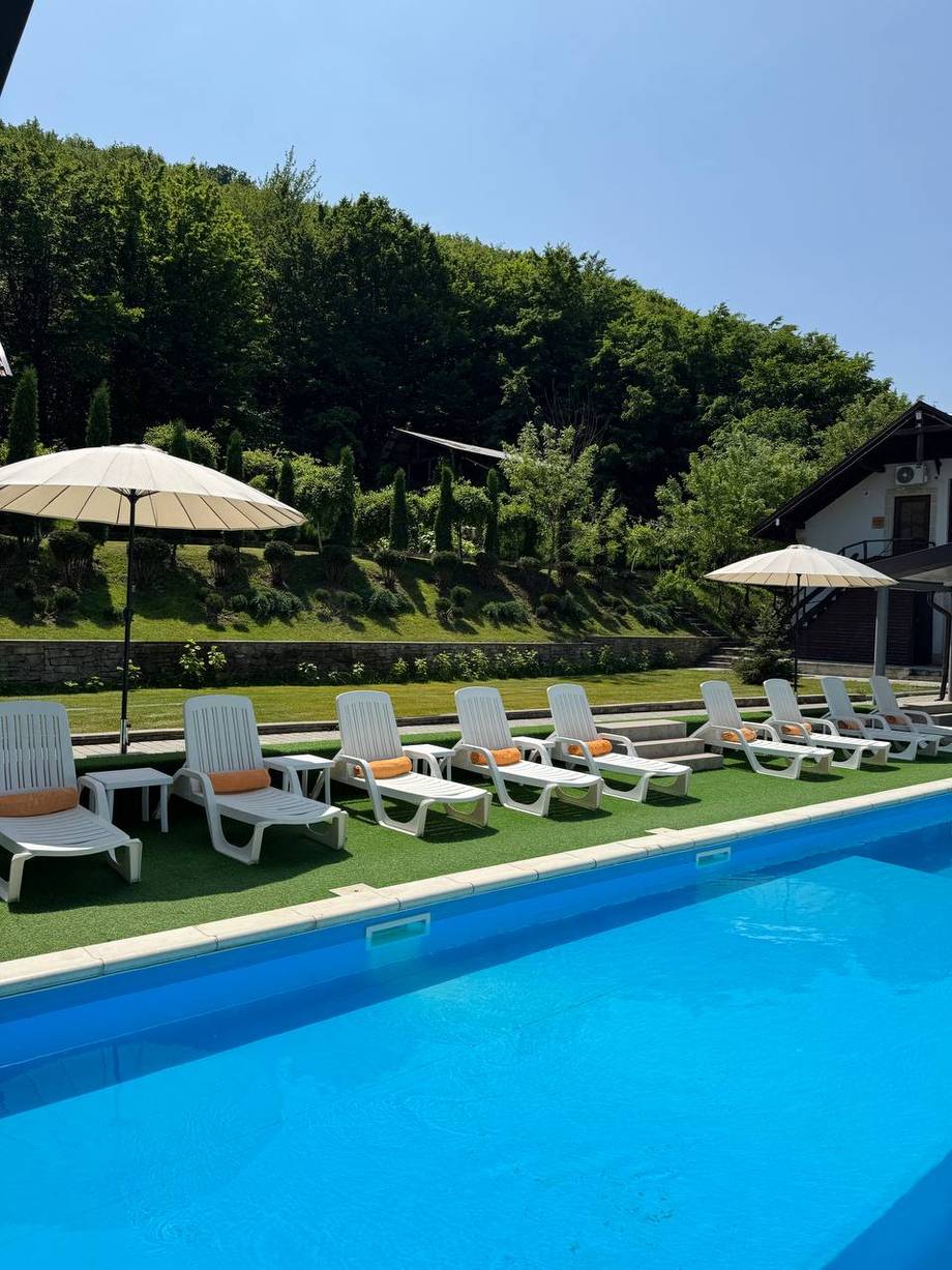 Resort pool area with loungers, umbrellas, and hillside setting