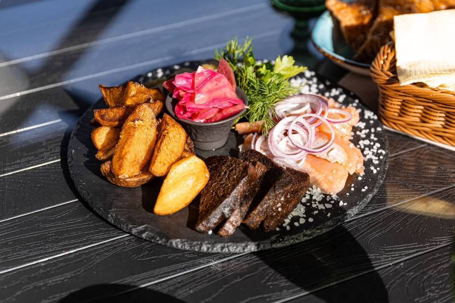 Grilled steak with roasted potatoes, fresh herbs, and microgreens on dark plate