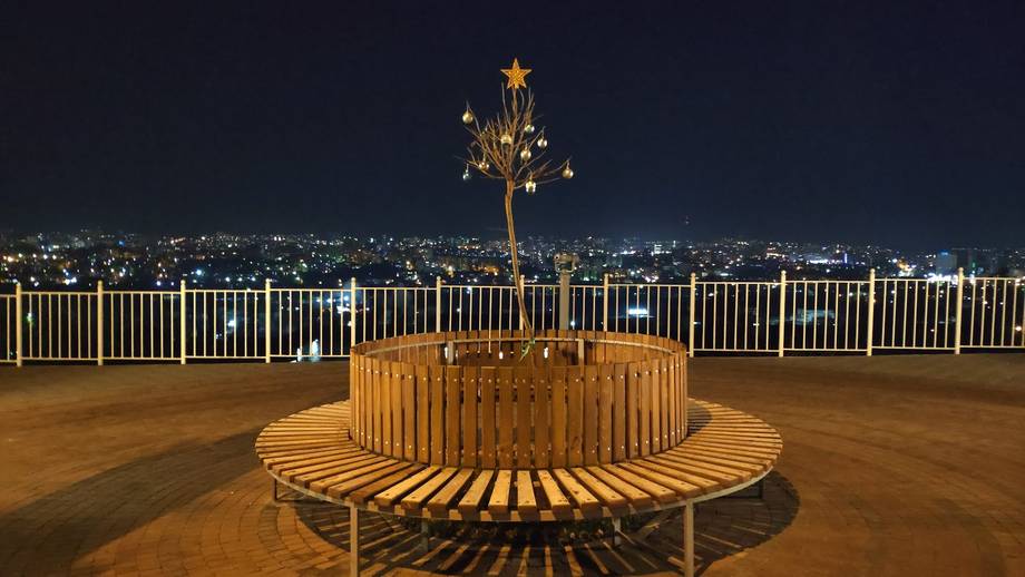 Rooftop terrace with wooden seating and city nightscape views