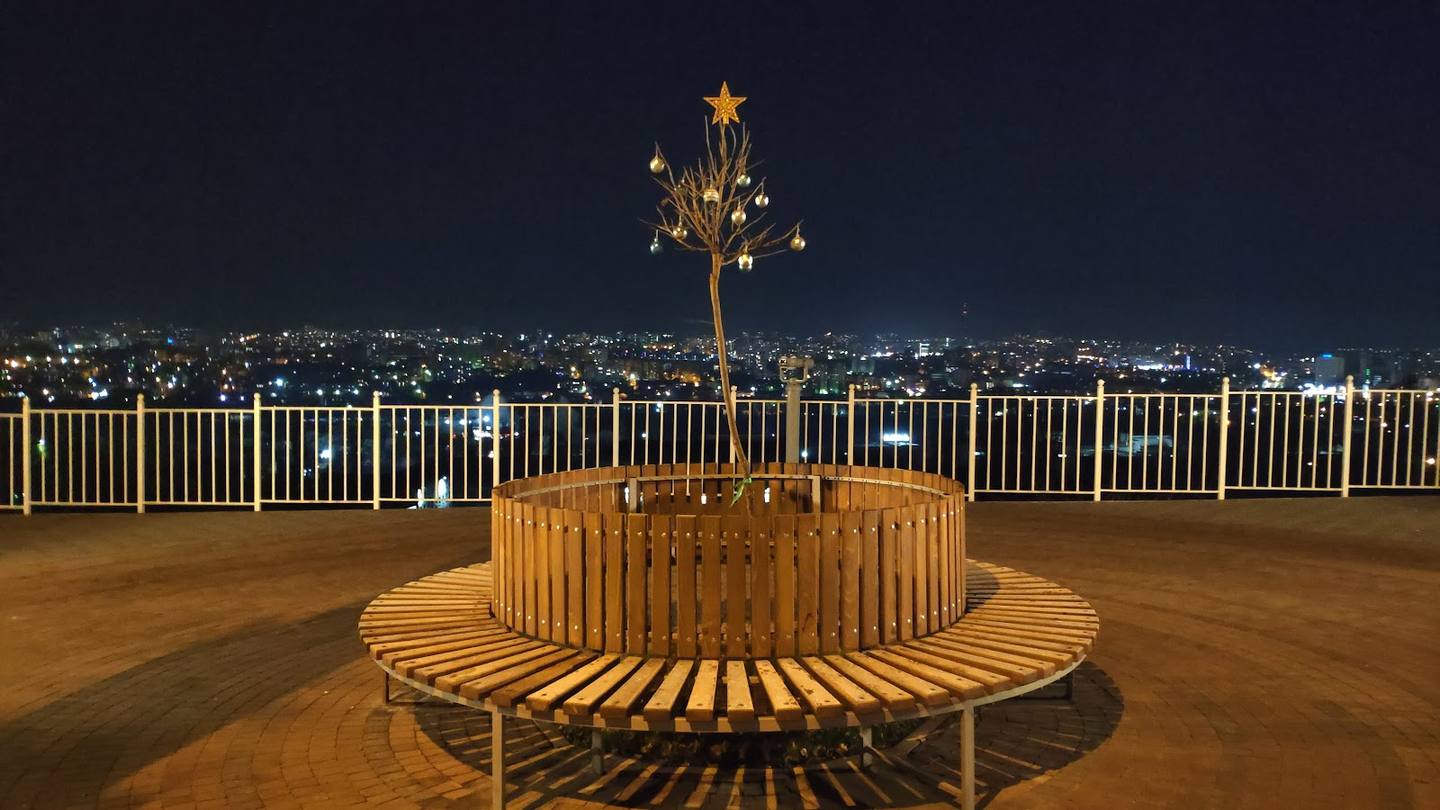 Rooftop terrace with wooden seating and city nightscape views
