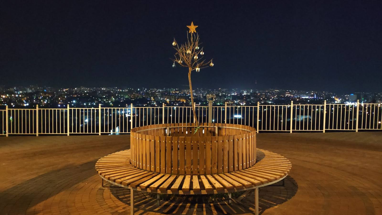 Rooftop terrace with wooden seating and city nightscape views