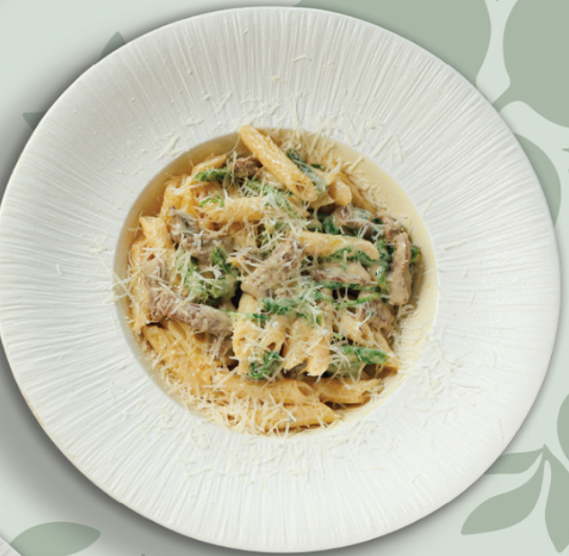 Creamy pasta dish with fresh herbs and grated cheese on white plate