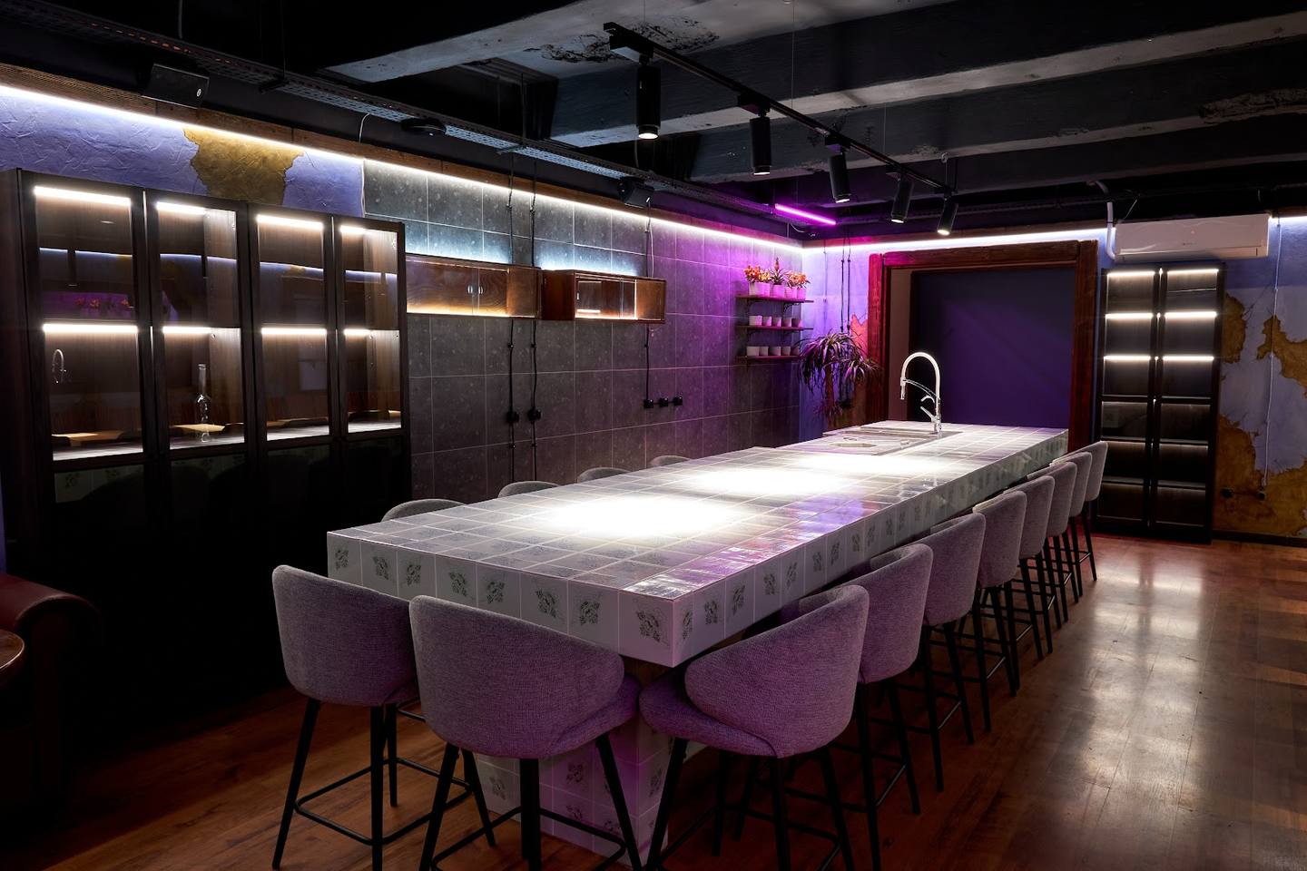 Modern bar interior with illuminated shelving, purple ambient lighting, and contemporary seating