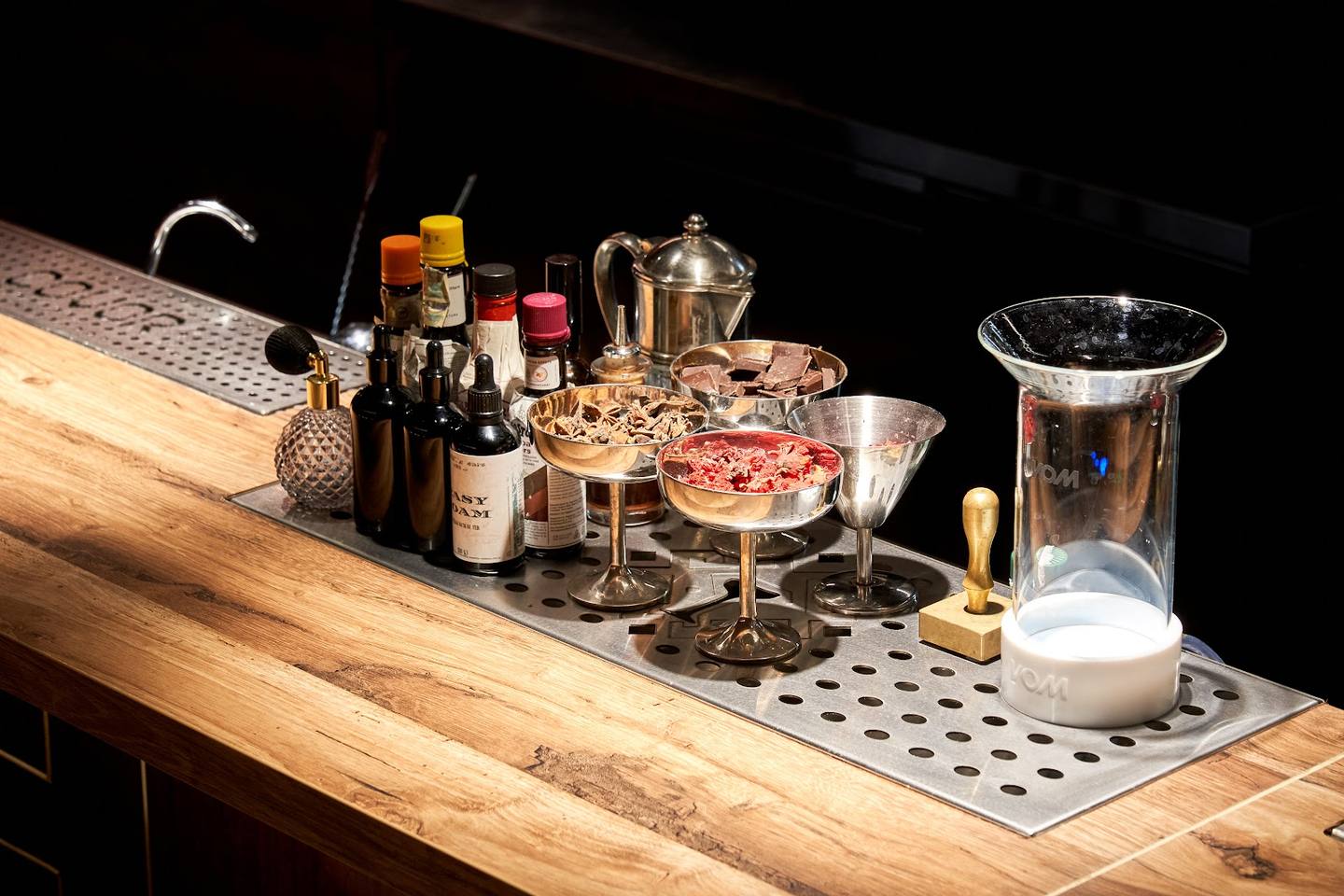 Bar setup with cocktails, bottles, and barware on wooden counter