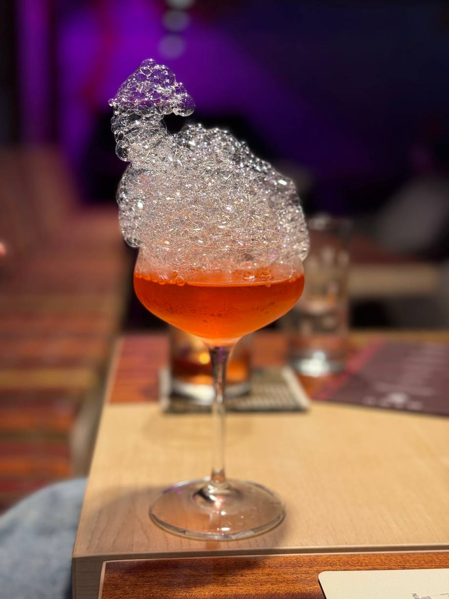 Craft cocktail with crystallized sugar rim and purple ambient lighting