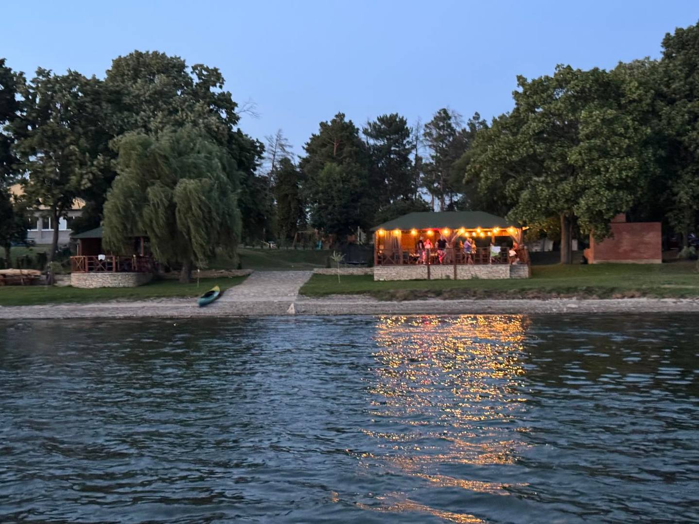 Riverside terrace venue with waterfront trees and evening ambiance