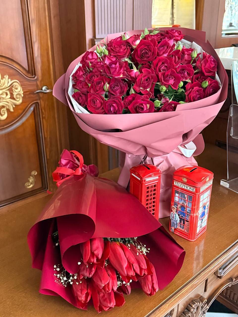Pink-wrapped roses and red flowers displayed on a wooden counter in an elegant interior