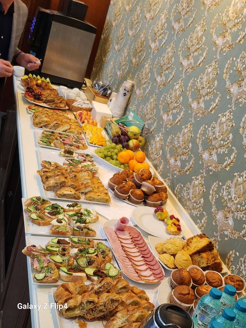 Catering spread with grilled fish, appetizers, cured meats, and pastries at event buffet