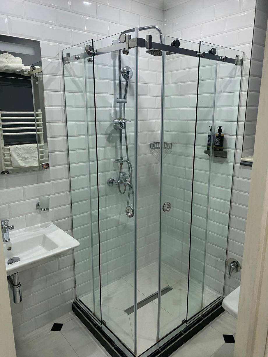Modern glass shower enclosure with rainfall showerhead in contemporary bathroom