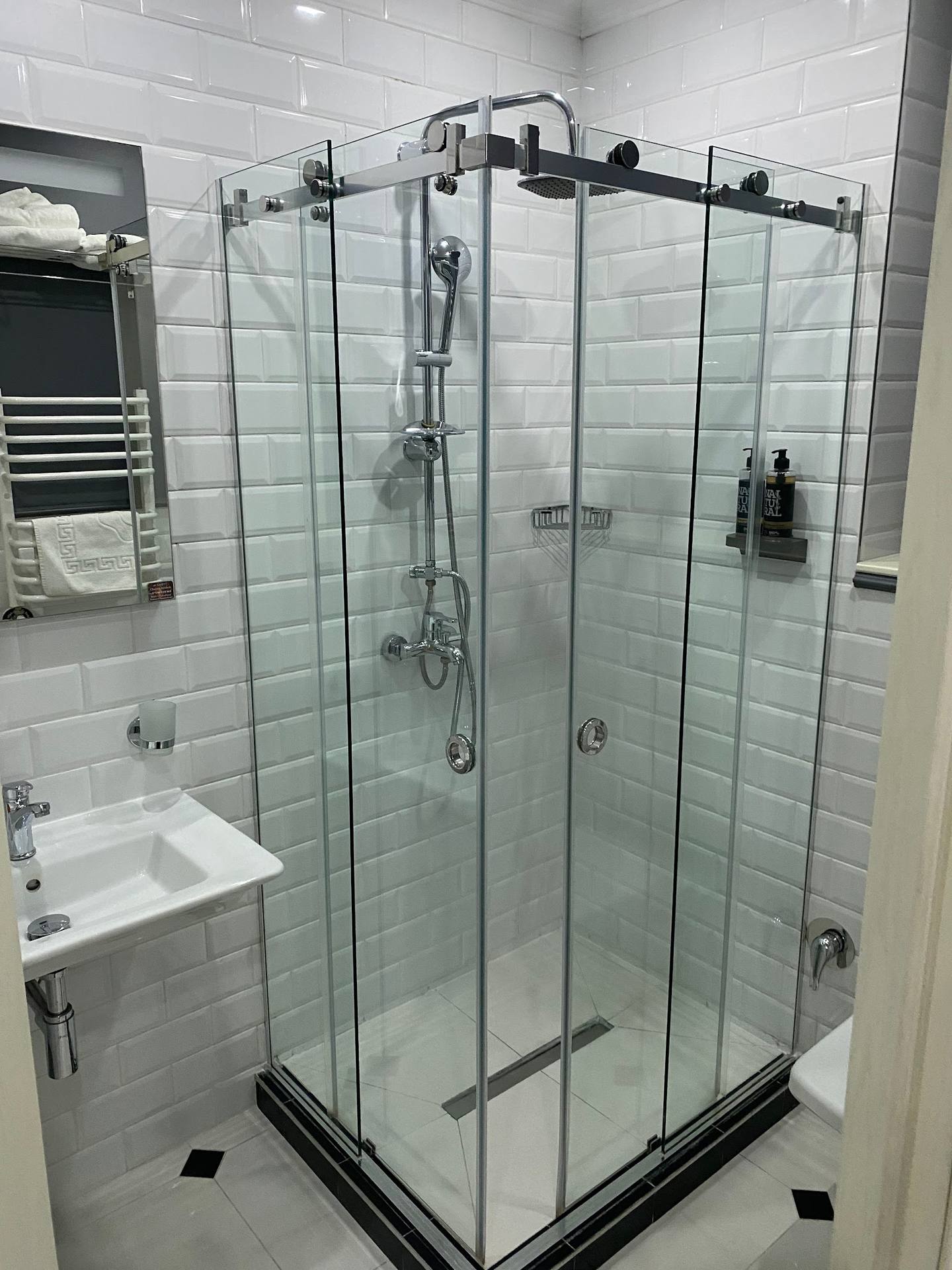 Modern glass shower enclosure with rainfall showerhead in contemporary bathroom