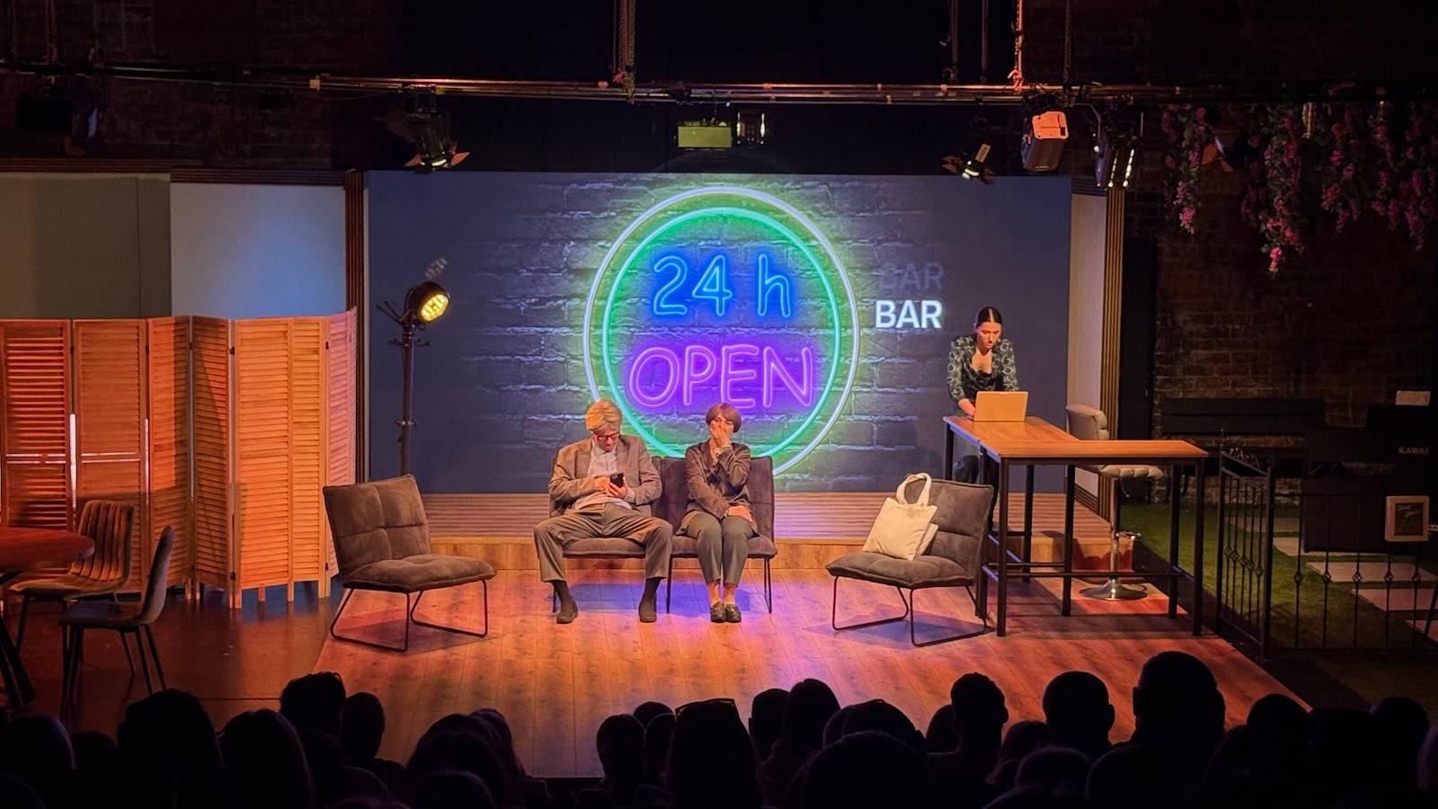 Event venue with stage, neon bar sign, audience seating, and performance setup