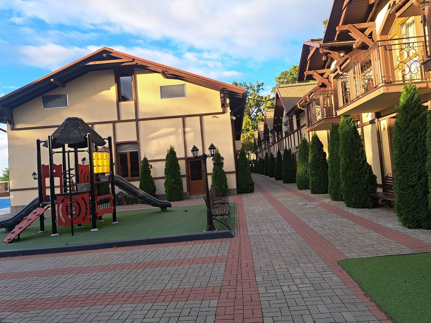 Modern exterior courtyard with cream-colored buildings, brick pathways, and landscaped grounds