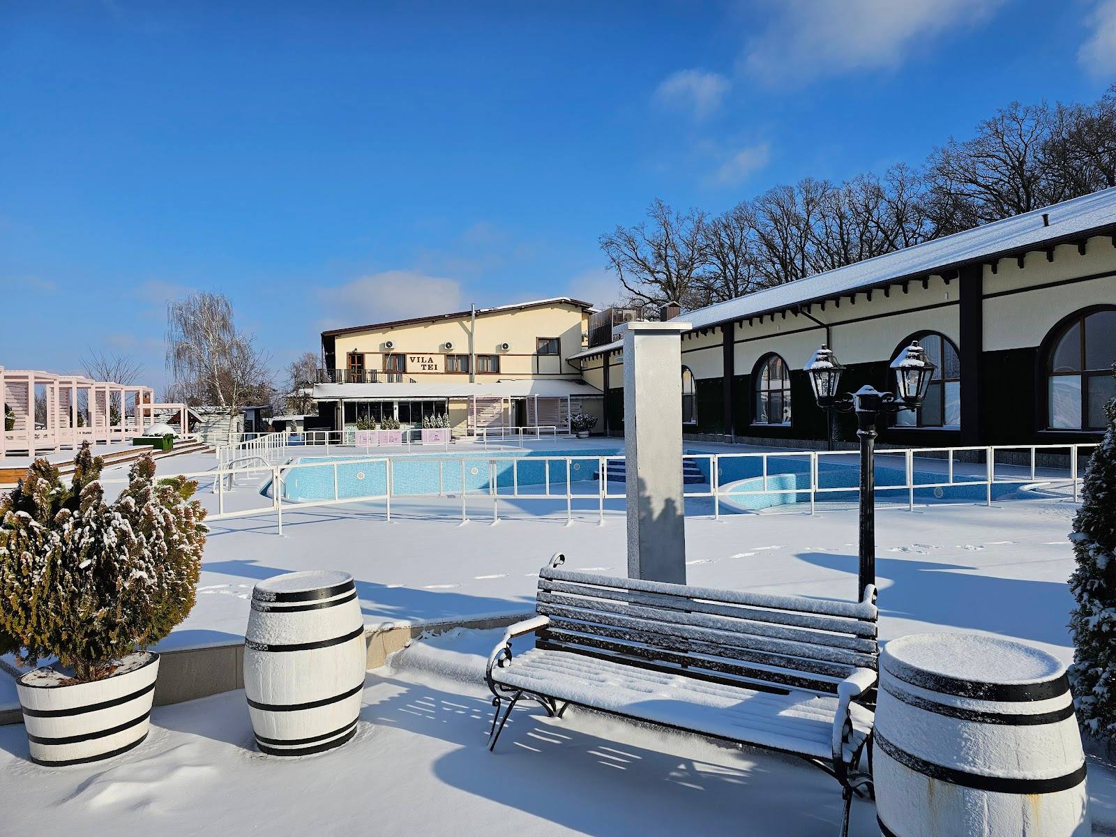Spa or wellness resort terrace with pool, winter seating area, and main building in background