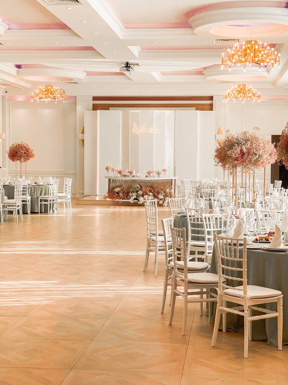 Elegant reception hall with coffered ceiling, chandeliers, and floral centerpieces