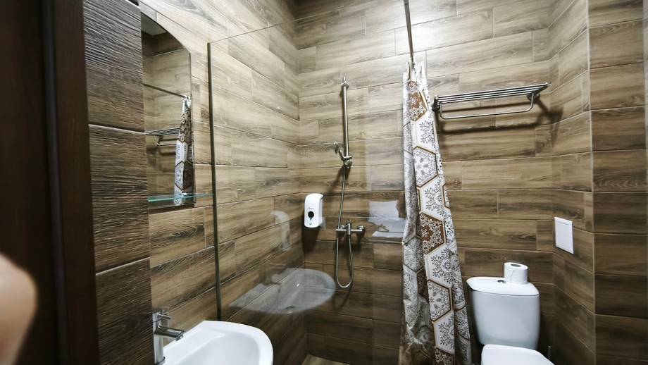 Modern bathroom with wood-tile walls, glass shower enclosure, and spa amenities