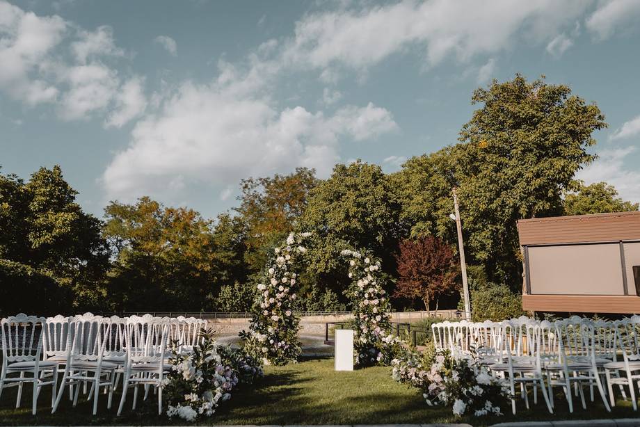 Outdoor ceremony grounds with white chairs, floral arch, and manicured lawn venue
