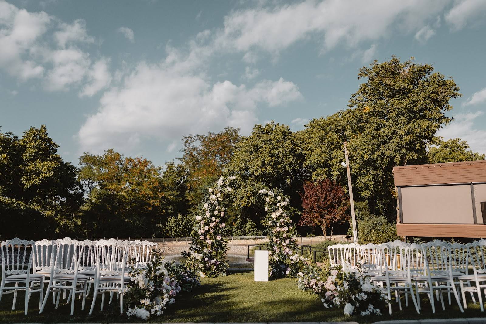 Outdoor ceremony grounds with white chairs, floral arch, and manicured lawn venue