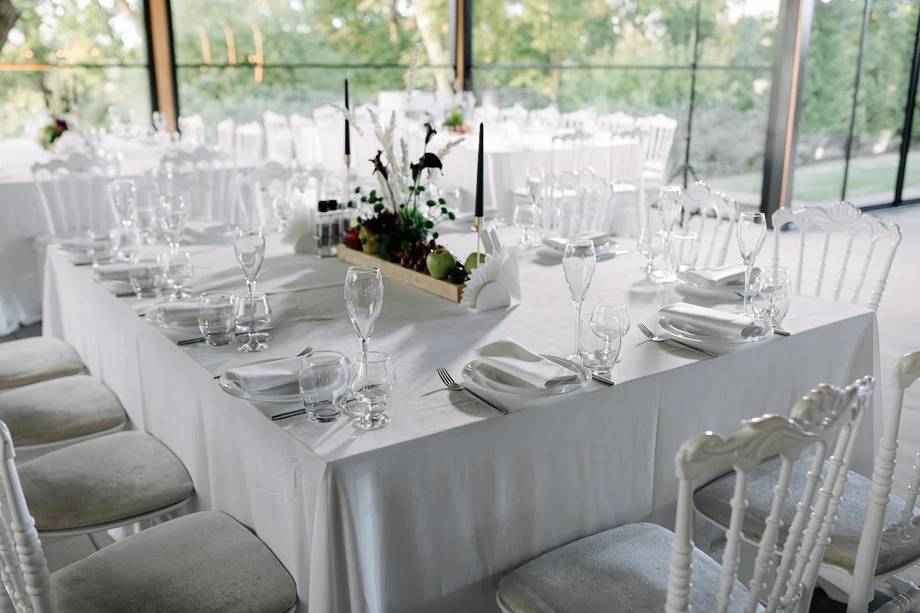 Elegant white-linened banquet table setup with floral centerpiece and place settings