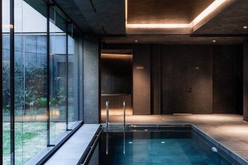 Indoor pool with ambient lighting and floor-to-ceiling windows overlooking landscaped grounds