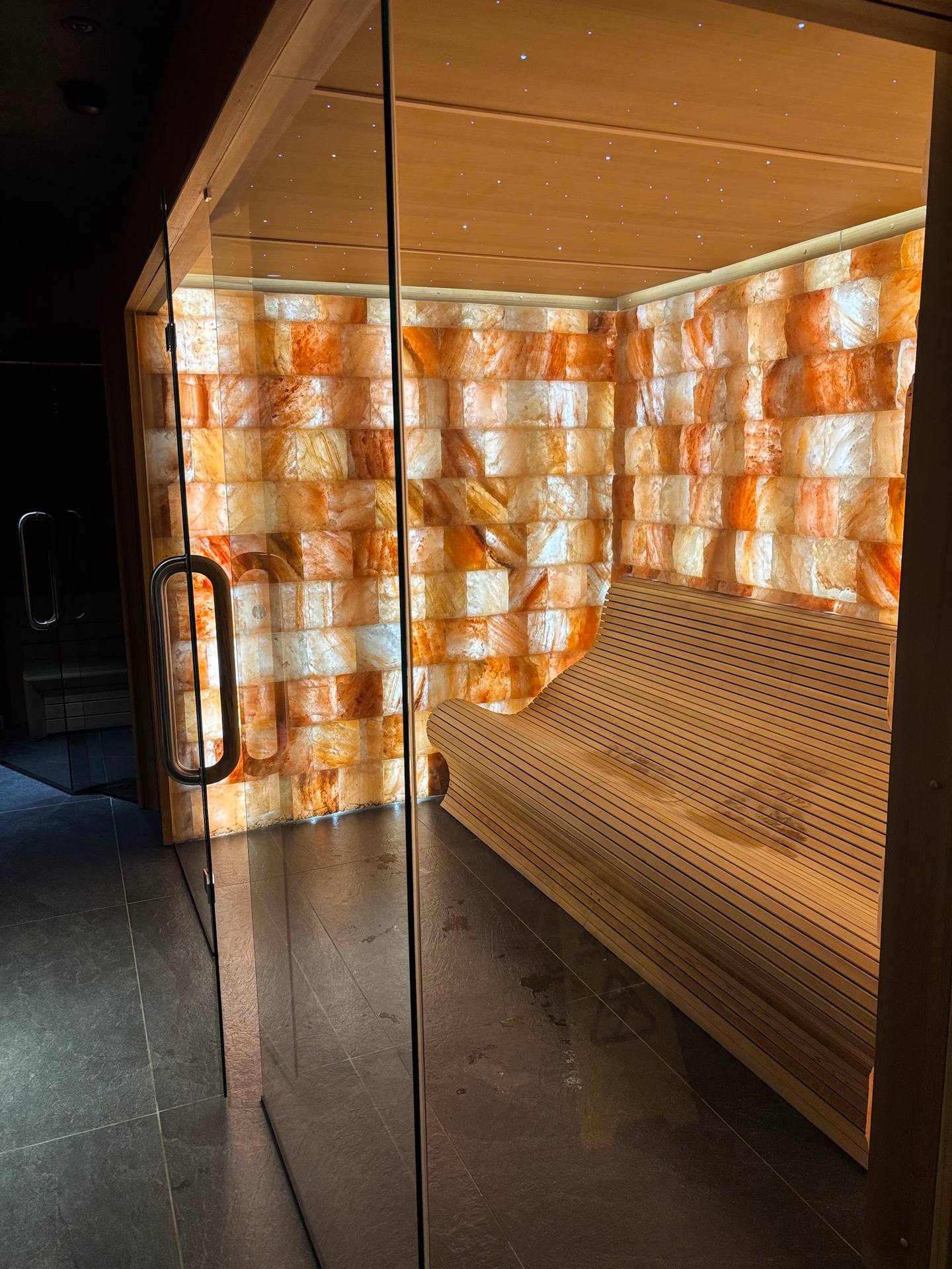 Salt therapy room with warm amber salt block walls and wooden sauna bench