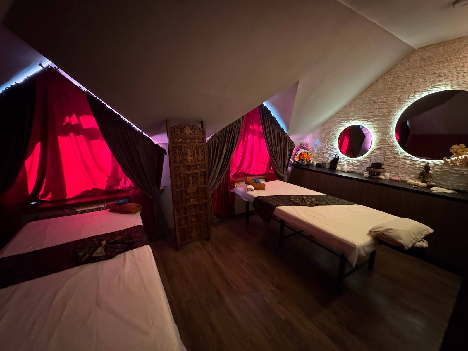 Spa treatment room with illuminated red fabric canopies and massage tables