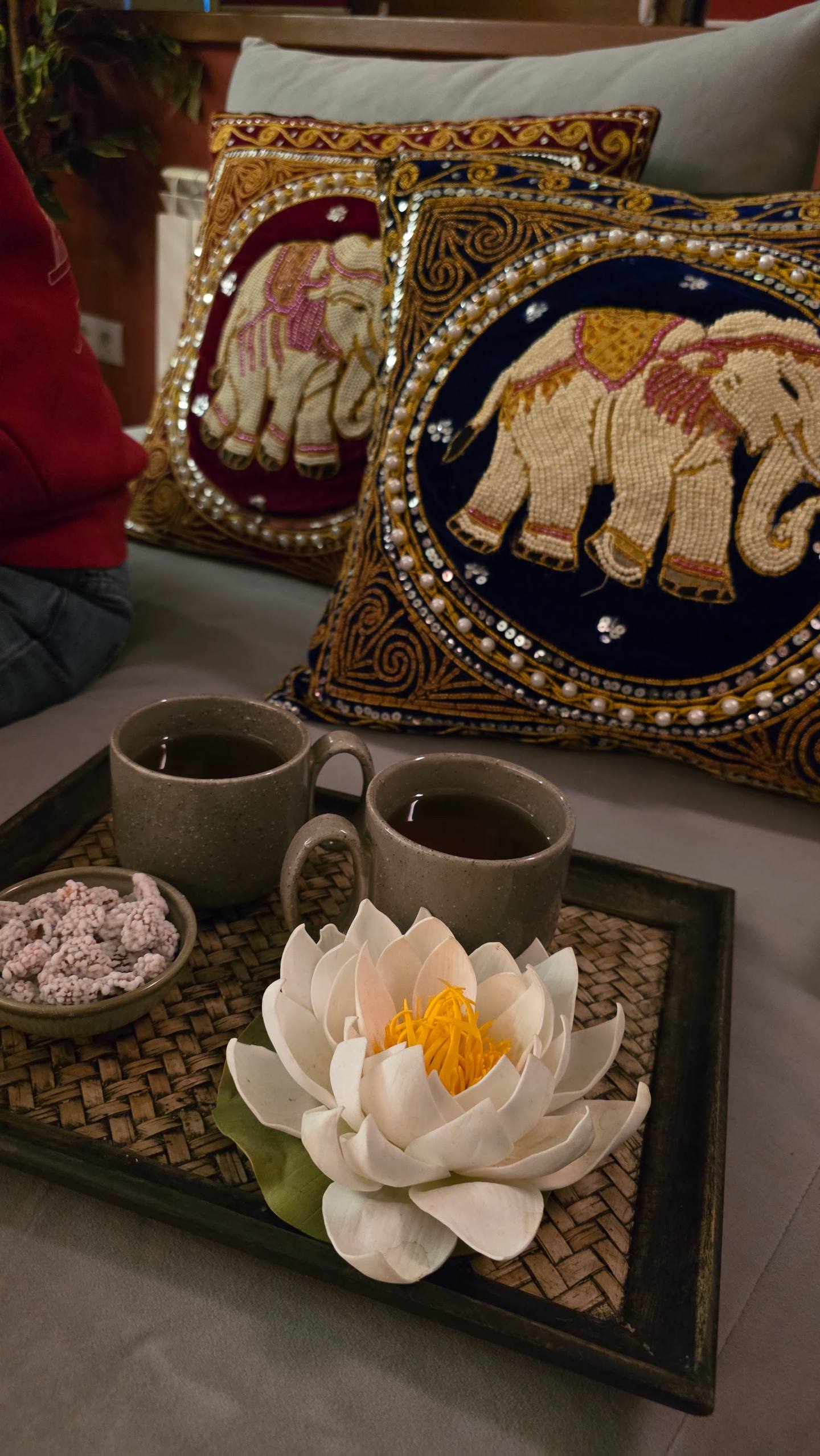 Styled table vignette with decorative pillows, tea service and lotus flower arrangement