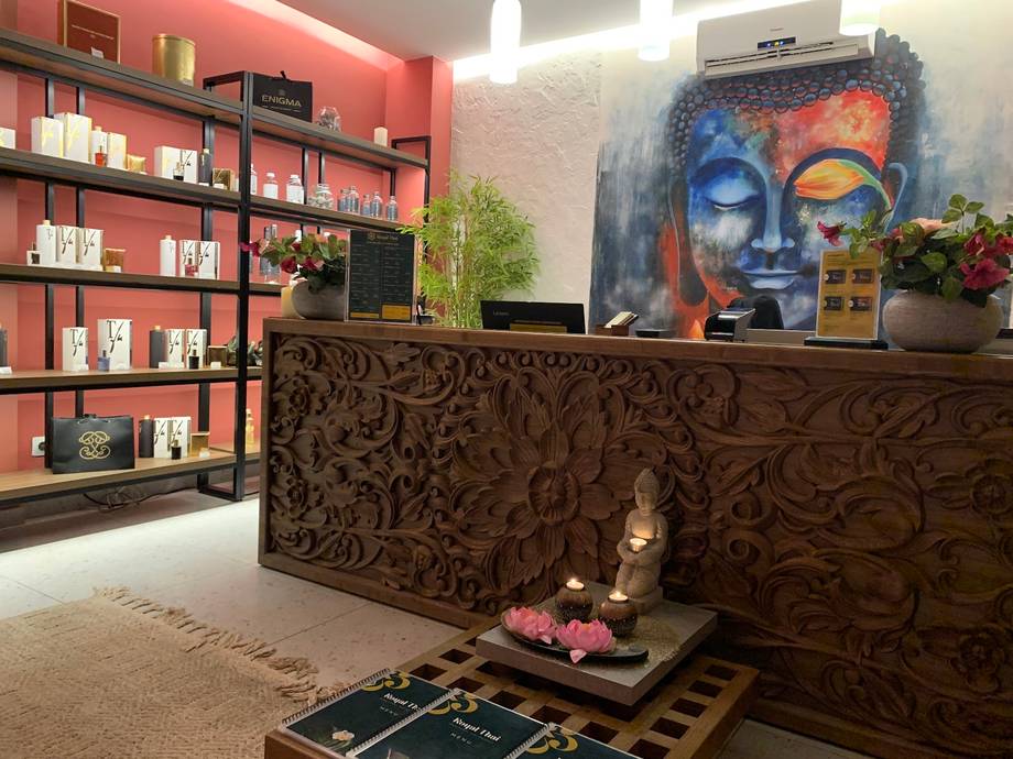 Spa reception area with ornate wood counter, colorful shelving, and wellness artwork